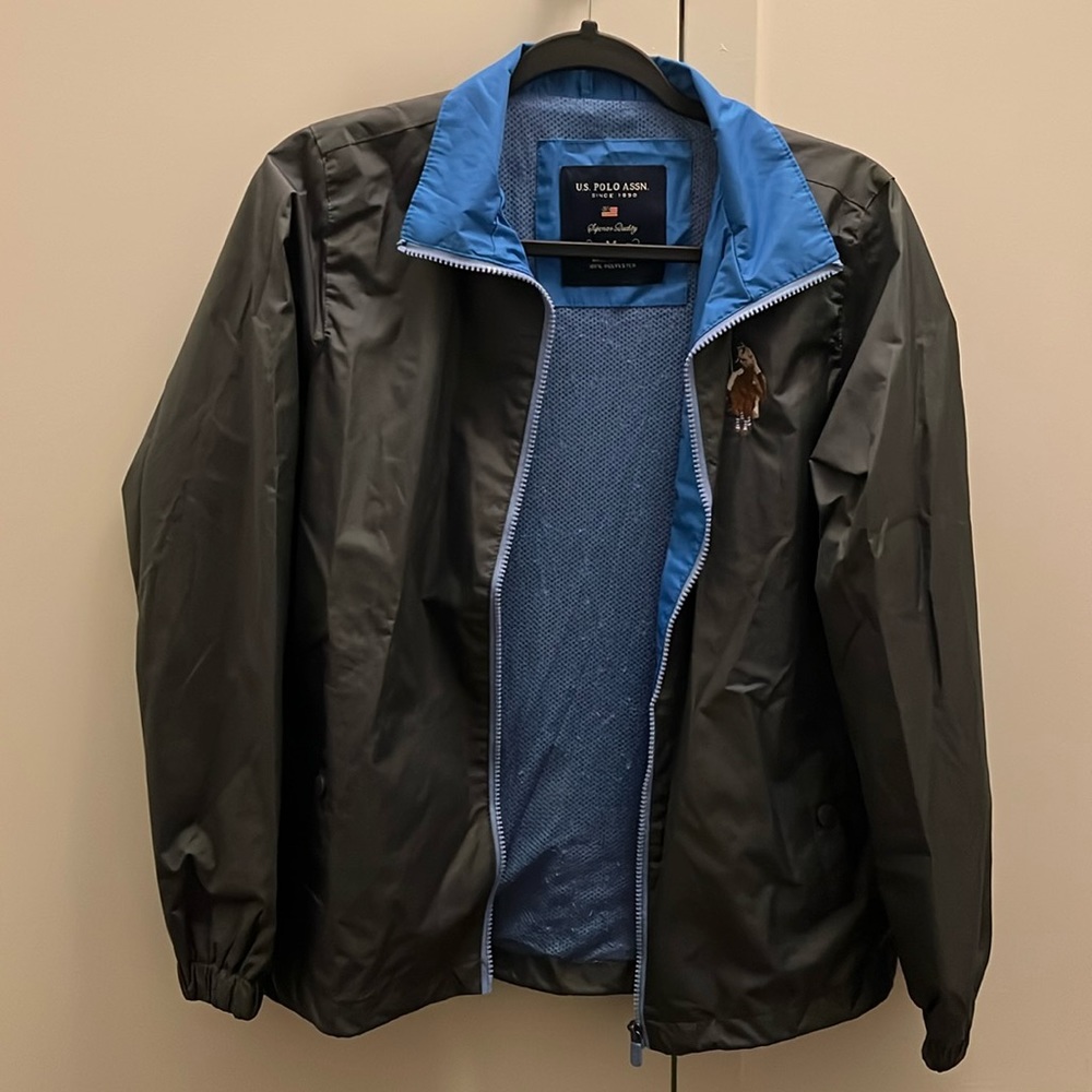 Dark gray windbreaker with blue zippers and collars